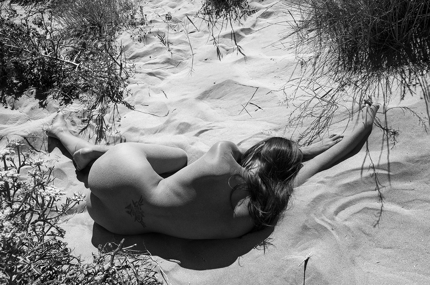 corps de femme allongée nue sur le sable